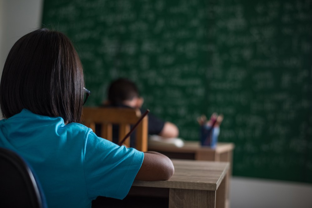 Estudiantes atentos frente a la pizarra en un aula de secundaria